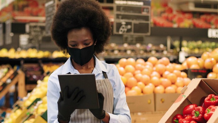 Arbeiterin im Supermarkt mit Maske und Handschuhen