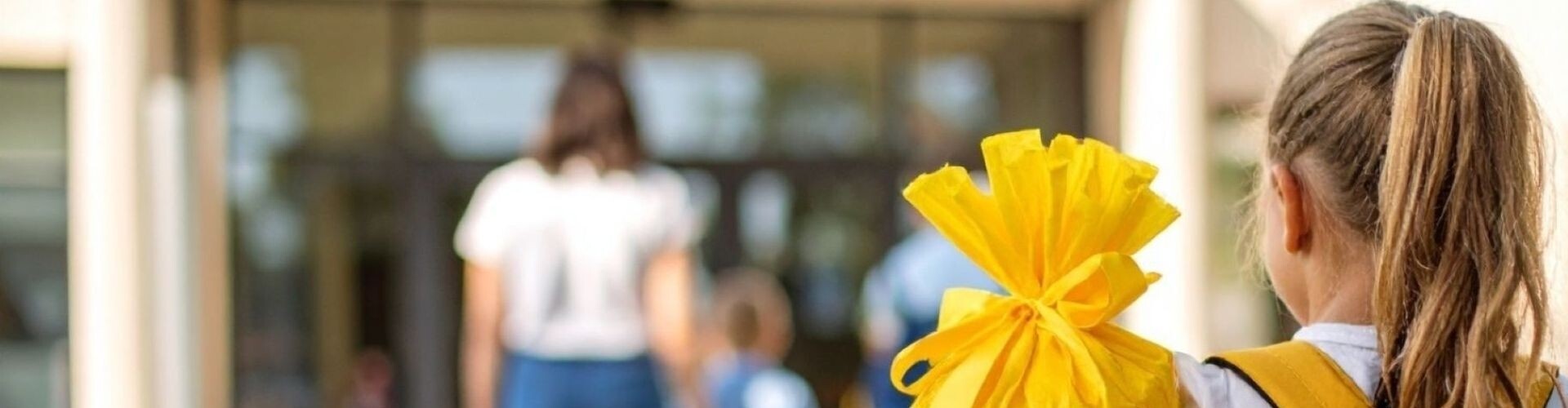 Kind mit gelber Schult&uuml;te auf dem Schulgel&auml;nde