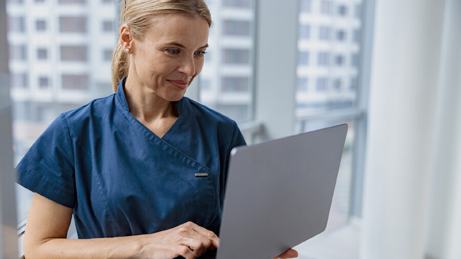 Junge Krankenpflegerin liest am Laptop