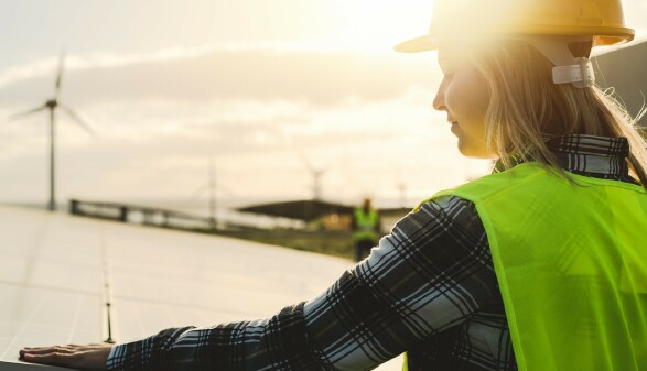 Junge Ingenieurin im Einsatz für alternative Energien mit Windrad und Solarpanel 