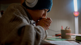 Ein Teenager macht seine Hausaufgabe in einer ungeheizten Wohnung.