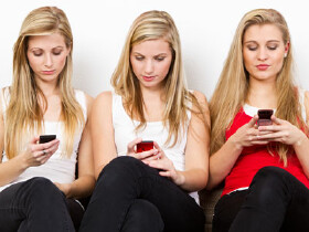 Drei junge Frauen spielen sorglos mit ihren Handys