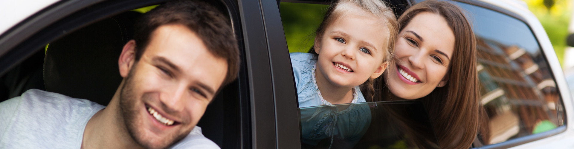 Mann blickt vom Fahrersitz aus dem Fenster eines weißen Autos, Frau und Kind blicken aus dem hinteren Fenster. © pikselstock, stock.adobe.com