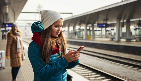 Mädchen mit Smartphone am Bahnsteig