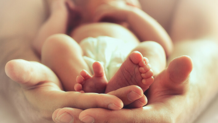 Eltern halten ein schlafendes Neugeborenes in ihrer Hand