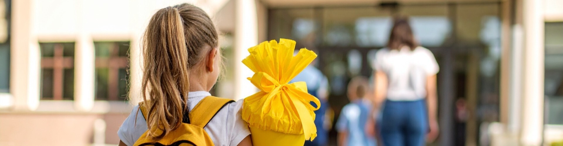  Kind mit gelber Schult&uuml;te auf dem Schulhof