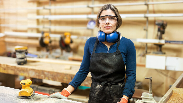 © AntonioDiaz, stock.adobe.com Junge Tischlerin mit Schutzbrille