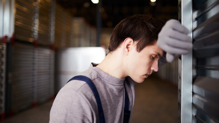 Junger Mann lehnt an einem gro&szlig;en Container