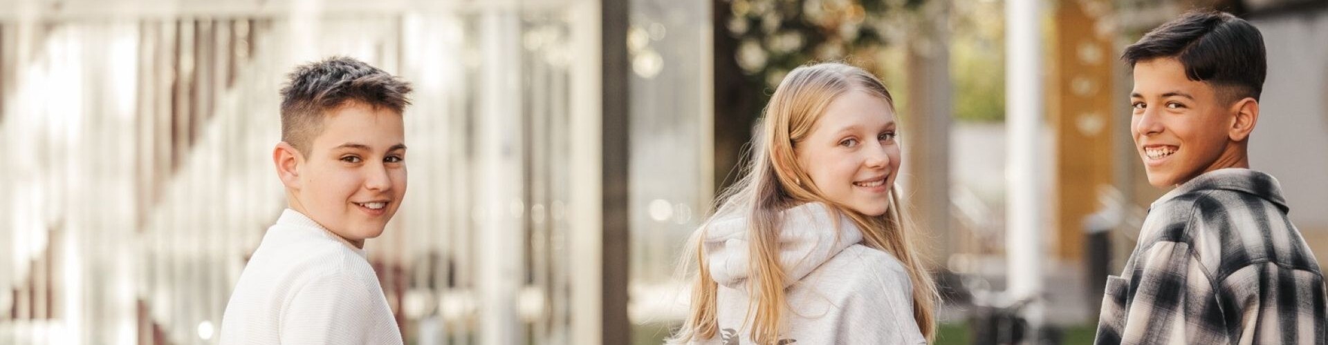 3 Sch&uuml;ler:innen l&auml;cheln in Richtung Kamera.
