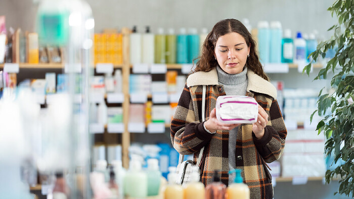 Junge Frau kauft Damenhygieneartikel